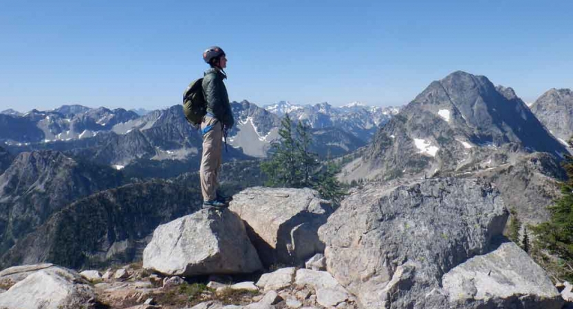 a person stands on a rock overlooking a vast mountainous landscape on an outward bound gap year expedition 